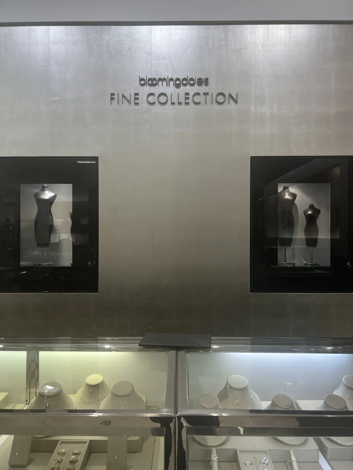 bloomingdale's FINE COLLECTION 金属招牌墙与下方灯柜里的项链陈列