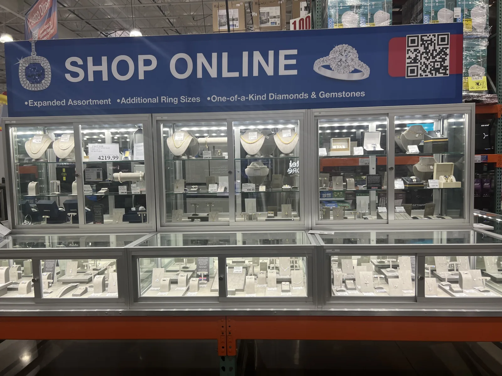 Costco 珠宝柜台上方 SHOP ONLINE 蓝色横幅,配二维码,主打线上更全的钻石与彩宝