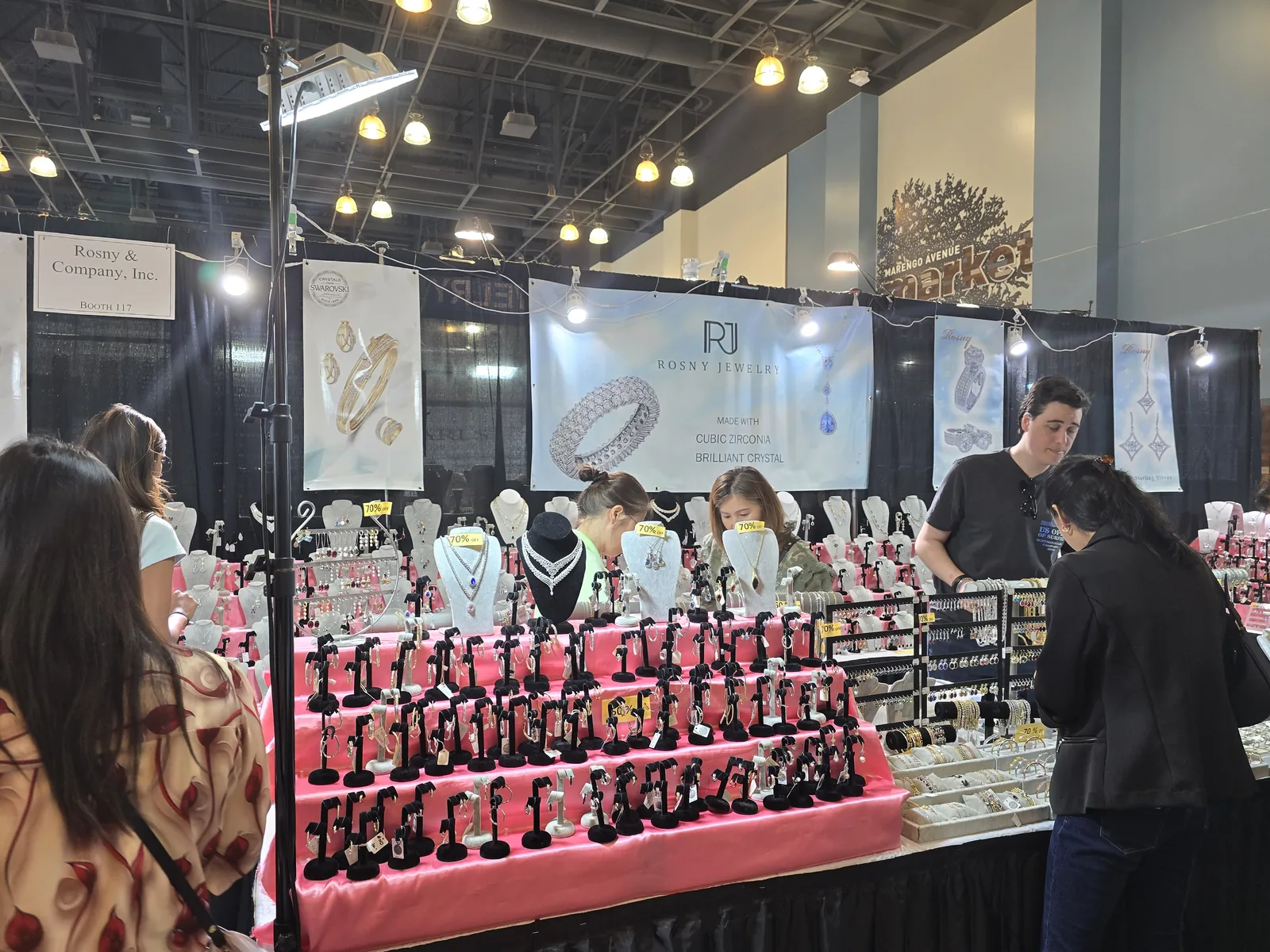 InterGem 展会成品珠宝摊位,红色颈托一排排挂项链,顾客在挑选