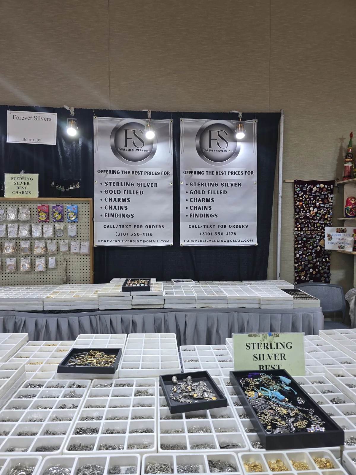 InterGem 展会 Sterling Silver 招牌下,白色挂板墙陈列银饰 charms 与吊坠,黑色展板