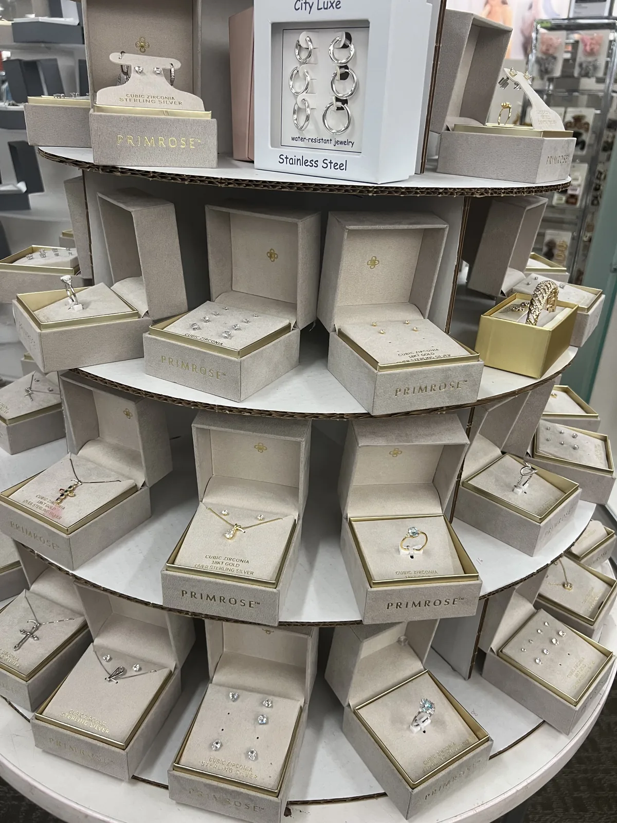 Kohl's Primrose 与 City Luxe 陈列塔,顶部 City Luxe water-resistant jewelry Stainless Steel 招牌,下方纯银锆石戒指耳钉吊坠